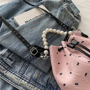 Sac seau rose avec imprimé lapin, anse en perles et bandoulière noire sur fond en jean