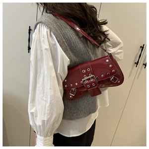 Detailed view of red patent leather punk style shoulder bag with silver rivets and buckle