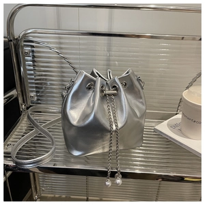 Detail of silver oil wax leather bucket bag with chain pearl charms and drawstring closure