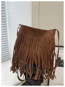 Detail shot of brown faux suede shoulder bag featuring long fringe bohemian tassels