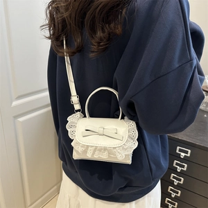 Mini borsa bianca a tracolla con bordo in pizzo e fiocco in pelle indossata a spalla