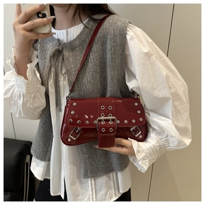 Détail du sac en cuir verni bordeaux avec clous argentés et boucles en selfie miroir