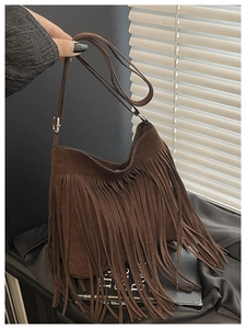 Detail of dark brown faux suede bag featuring long fringe tassels and silver metal buckle