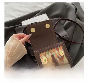 Detail of dark brown leather crossbody bag with geometric woven panel and gold magnetic clasps