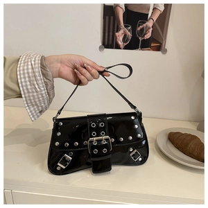 Close-up of black patent leather underarm bag with silver studs and punk metal details