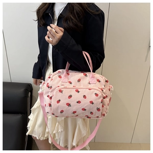 Dettaglio della borsa tote in velluto rosa con motivi a fragola e tasca frontale con zip