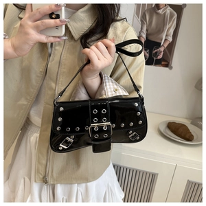 Close-up of black patent leather underarm bag featuring punk style silver studs and buckle