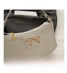 Detail shot of white litchi pattern leather bag with a golden bow buckle and floral zipper