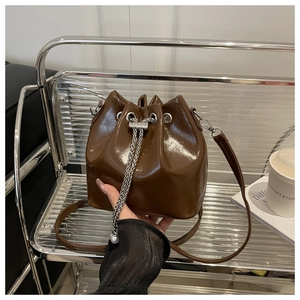 Borsa a secchiello marrone scuro lucido in pelle cerata con coulisse a catena argento