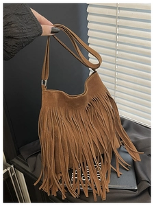 Close-up of brown suede crossbody bag featuring long bohemian tassels and soft texture