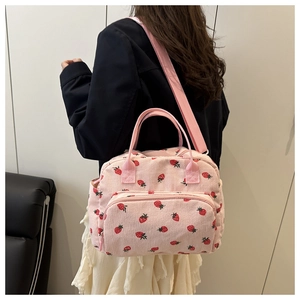 Borsa in velluto a coste rosa con motivi a fragola portata a spalla, vista laterale