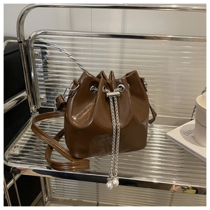 Detail of coffee brown bucket bag with shiny PU leather and pearl chain drawstring
