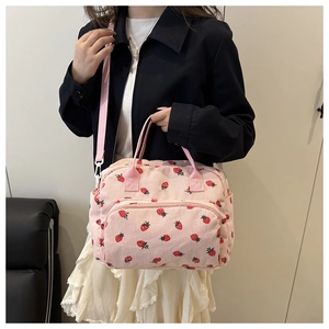 Detail of pink corduroy strawberry bag featuring front zipper and side pockets