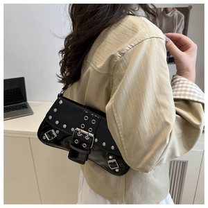 Detail of black patent leather shoulder bag with silver rivets worn by a model