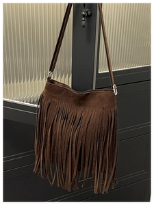 Close-up of brown suede crossbody bag with long fringe tassels and silver metal buckle