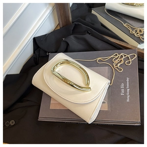Détail du sac carré crème avec poignée en D dorée et fine bandoulière chaîne