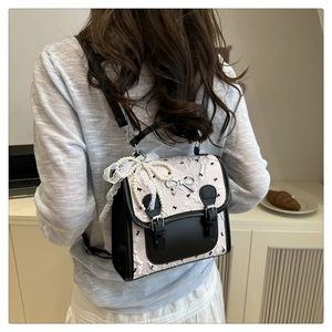 Détail du sac à dos plissé rose avec motifs nœuds noirs et breloque en perles