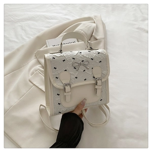 Détail d'un mini sac à dos blanc crème avec texture plissée et fermoir nœud en métal