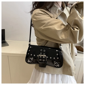 Close-up of black patent leather underarm bag featuring silver rivets and metal buckle detail