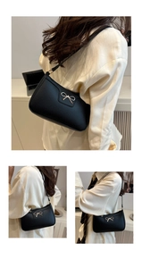 Close-up of black litchi grain leather shoulder bag with golden bow hardware detail