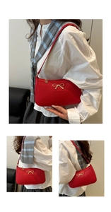 Macro shot of red pebble leather bag featuring a gold bow accent and fine stitching