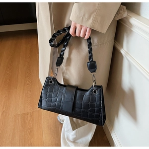 Macro detail of black crocodile pattern faux leather shoulder bag with woven handle