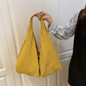 Detail of yellow pleated tote bag with drawstring texture shown in casual style