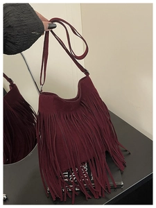 Detail of burgundy suede crossbody bag with long fringes and adjustable strap