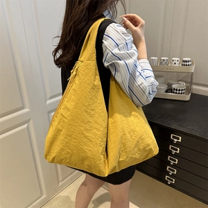 Detail of a large mustard yellow pleated nylon hobo tote bag with zipper closure