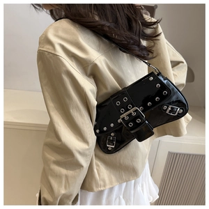 Close-up of black patent leather underarm bag with silver rivet details and buckles