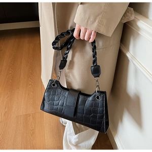 Detailed close-up of black crocodile pattern leather texture and braided handle
