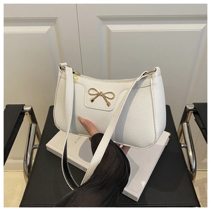 Close-up of white lychee texture handbag featuring a golden bow metal buckle detail