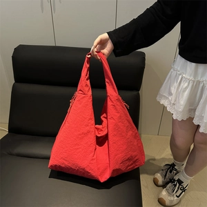 Detail of red triangular tote bag showing lightweight nylon fabric and drawstring side accents