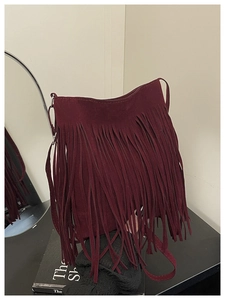 Detailed macro shot of vintage burgundy suede fringe and texture on a shoulder bag