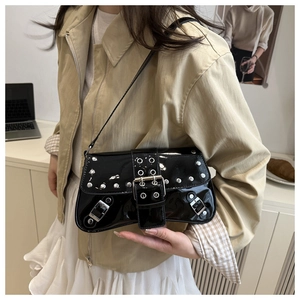 Detail view of black patent leather underarm bag with silver rivets and buckle