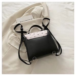 Vue de dessus d'un mini sac à dos pour femme avec broderie florale blanche sur rabat en cuir
