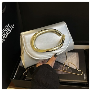 Détail du sac argenté avec grand anneau doré et bandoulière en chaîne élégante