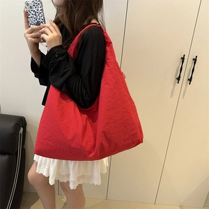 Detail of red nylon tote bag with pleated texture and wide comfortable shoulder strap