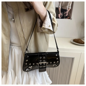 Detail of black patent leather shoulder bag with silver studs and rivet accents