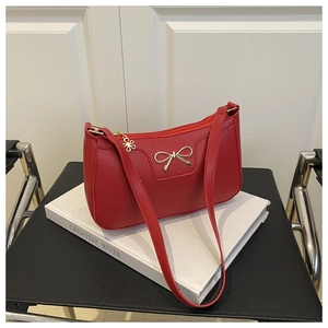 Detail of red lychee textured baguette bag with metal bow and floral zipper puller