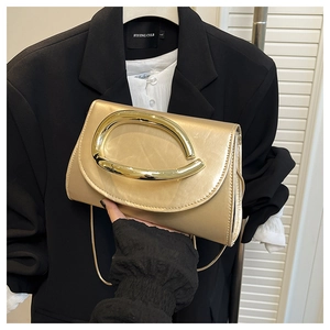 Détail d'une pochette enveloppe en satin doré champagne avec grande boucle en métal