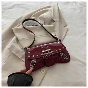 Close-up of wine red patent leather shoulder bag with silver studs and Y2K metallic buckles