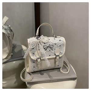 Détail du sac à dos en PU crème et dentelle avec nœud en perles et motifs rubans