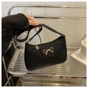 Close-up of black lychee grain leather bag with gold bow clasp and flower zipper