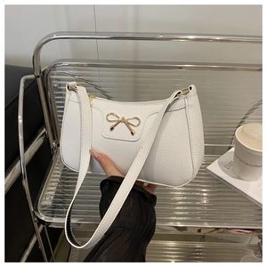 Close-up of white lychee pattern PU leather bag featuring a gold metal bow buckle