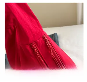 Detail of red tote bag featuring double zippers with rope pullers and textured fabric