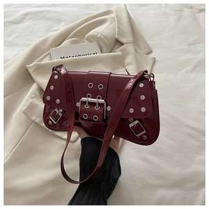 Detail of wine red patent leather shoulder bag with silver rivets and metal buckle