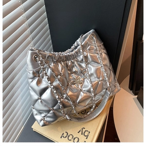 Detail of silver quilted bucket bag with star ornament and chain strap texture