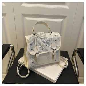Détail du sac à main blanc crème avec nœuds en perles dentelle et texture gaufrée