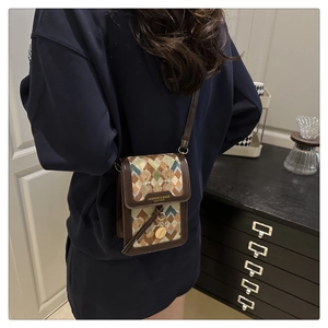 Detail showing vintage plaid fabric and brown leather trim on a stylish crossbody bag